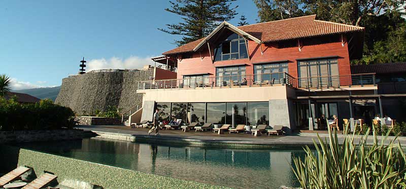 Hauptgebäude und Pool des Choupana Hills mit Holzfassade und Natursteinmauer