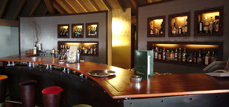 Hotelbar des Choupana Hills mit dunklem Holz und beleuchteten Flaschenregalen
